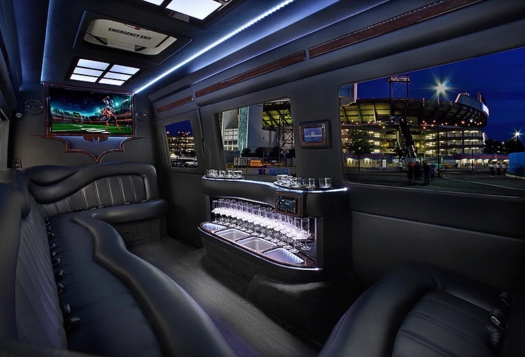 Leather lounge seats, bar and TV inside a VIP Sprinter